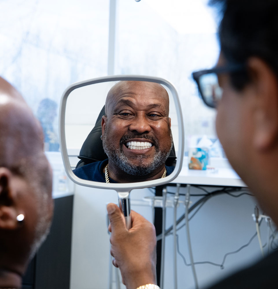 Patient smiling looking into mirror after dental procedure